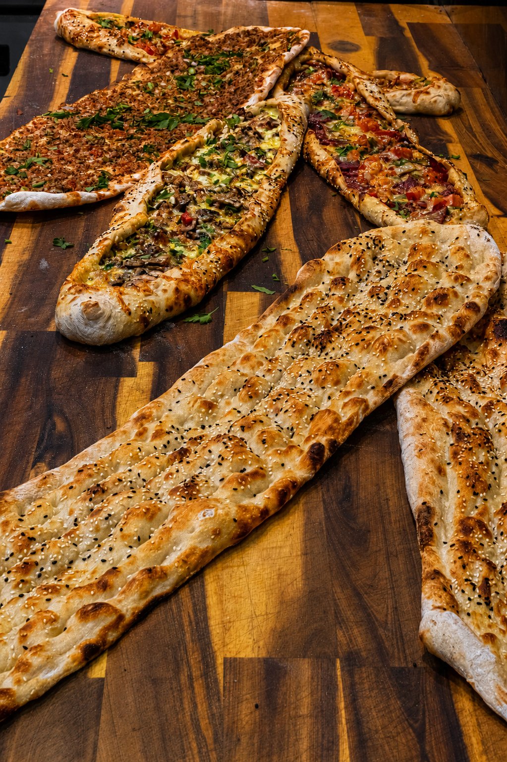 Freshly baked Turkish pides and flatbread on a wooden board at Reyhan